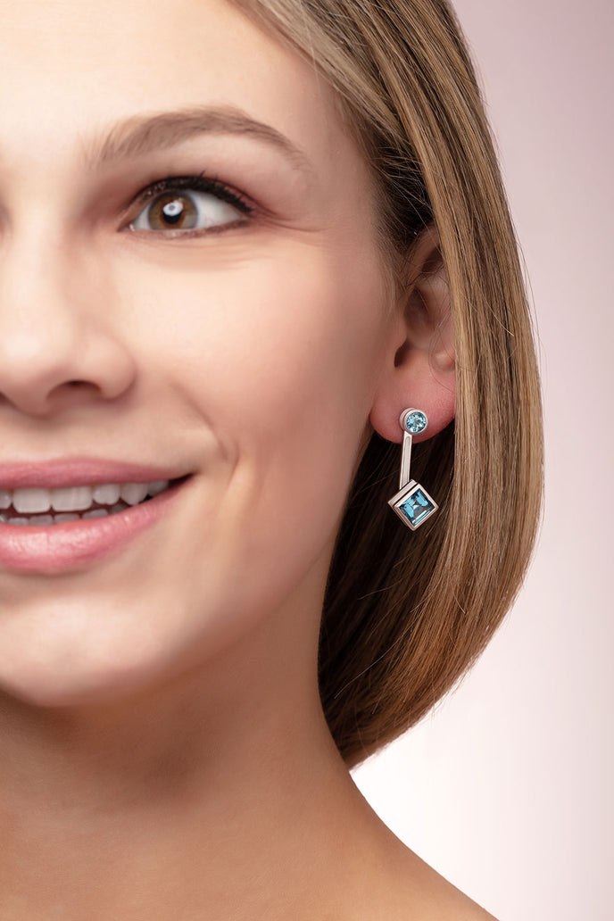 ‘Mix and Match’ earring drops with a pair of square Ostro Blue Topaz set in sterling silver paired with our ‘Play by ear’ stud earrings with a pair of round Ostro Blue topaz set in Sterling Silver being worn by model