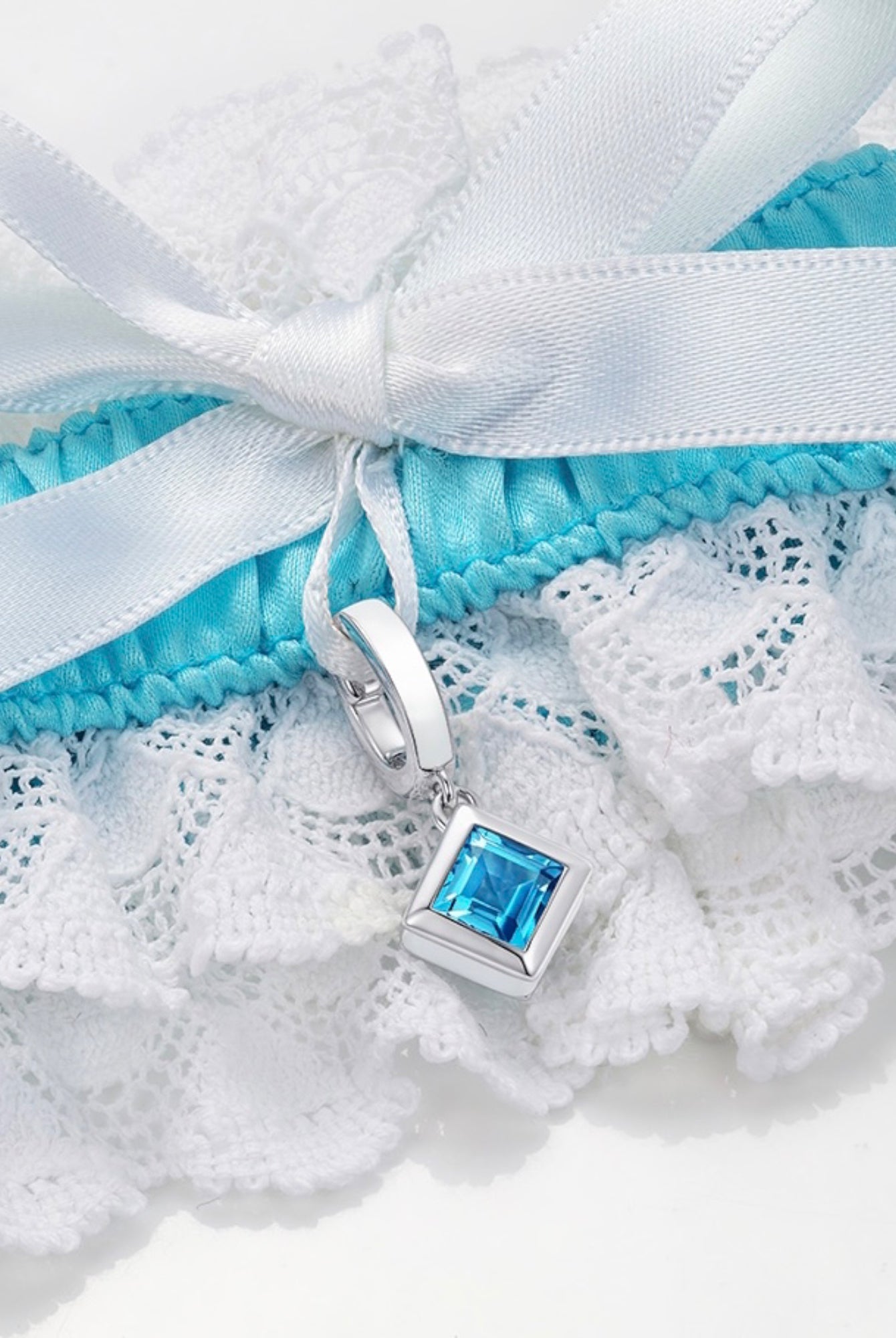 closeup of blue and white garter with square blue topaz charm
