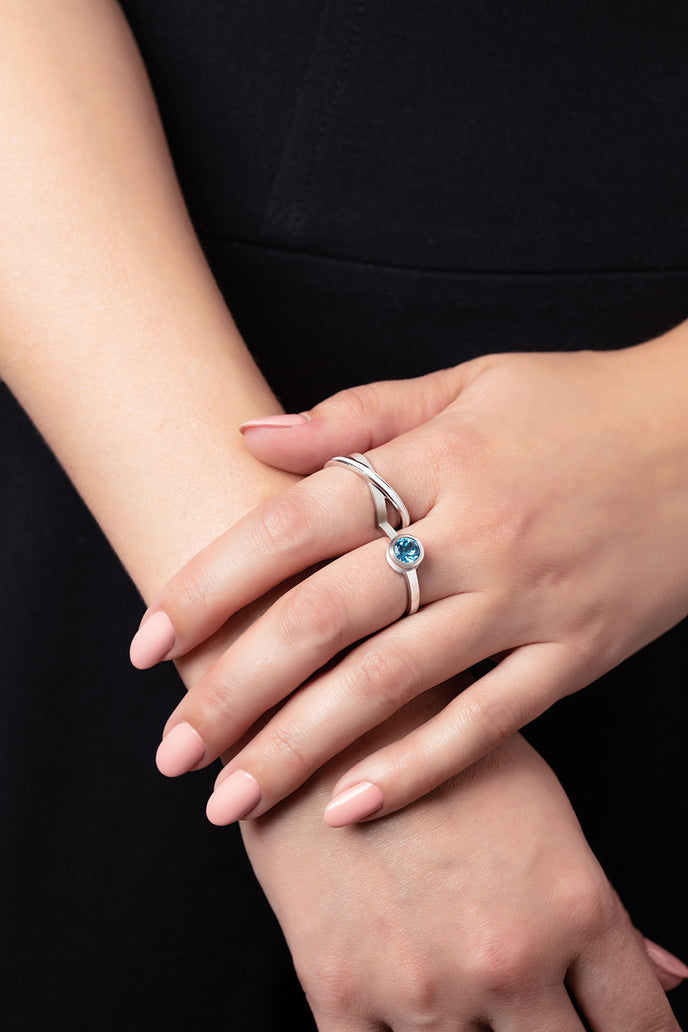 ‘Two of a kind’ double finger ring with a round Ostro Blue Topaz set in sterling silver being worn by model