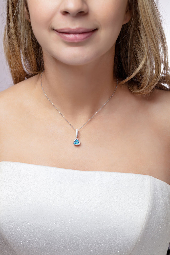Our model wearing ‘Tradition with a twist’ charm with a heart Ostro Blue Topaz set in Sterling Silver on a necklace