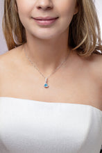 Load image into Gallery viewer, Our model wearing ‘Tradition with a twist’ charm with a heart Ostro Blue Topaz set in Sterling Silver on a necklace
