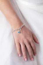 Load image into Gallery viewer, Our model wearing ‘Tradition with a twist’ charm with a heart Ostro Blue Topaz set in Sterling Silver on a bracelet
