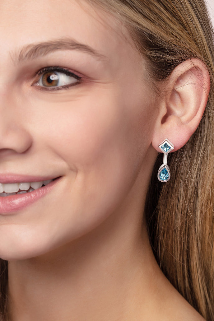 ‘Mix and Match’ earring drops with a pair of pear Ostro Blue Topaz set in sterling silver paired with our ‘Play by ear’ stud earrings with a pair of round Ostro Blue topaz set in Sterling Silver being worn by model
